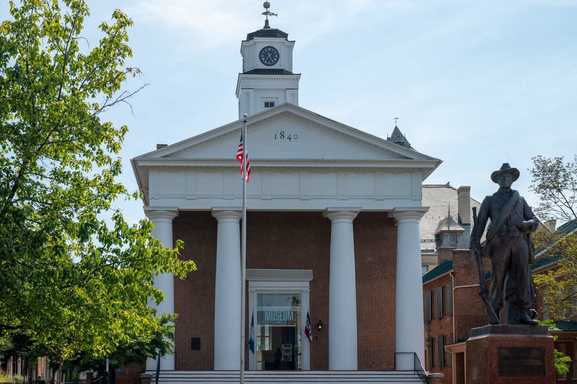 Historic courthouse facade with statue and American flag in daylight.