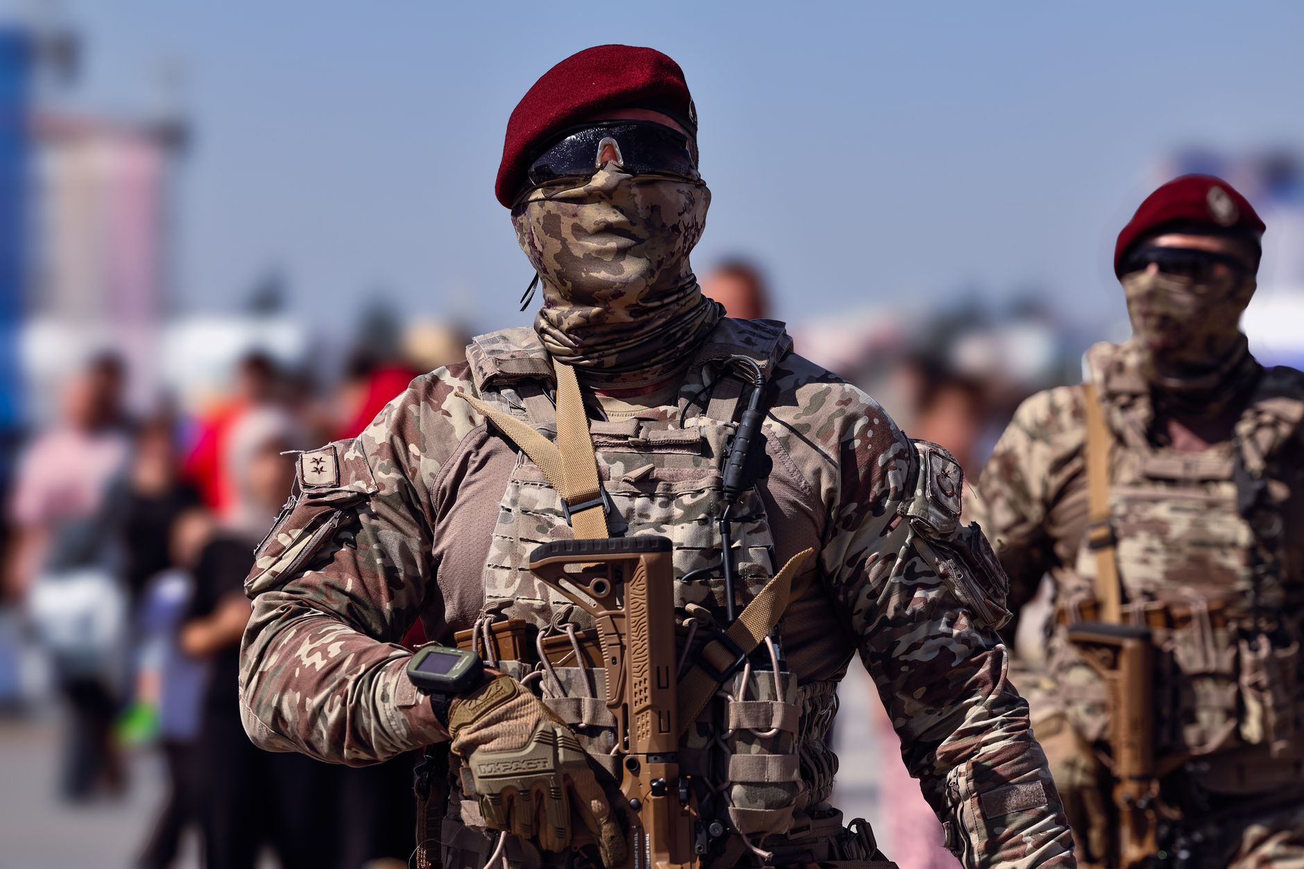 Armed Turkish commandos in camouflage gear marching outdoors during the day.