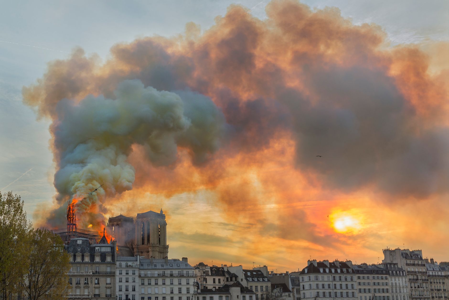 Smoke billows from Notre Dame Cathedral as it burns during sunset in Paris, France.
